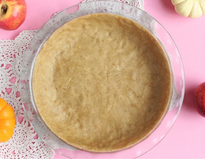 Overhead shot of pie crust with a pink background.