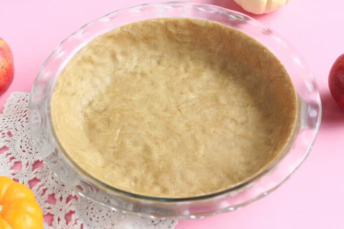 Side shot of a pre-baked pie crust in a clear glass pie pan.