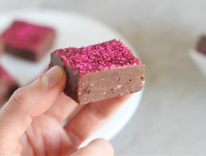 Hand holding a piece of chocolate fudge with pink sprinkles.