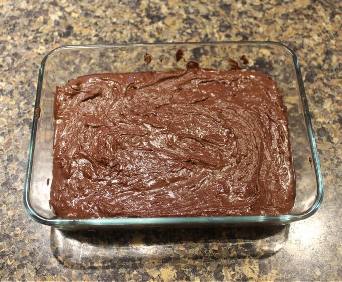 Chocolate fudge batter spread into a rectangular glass dish.