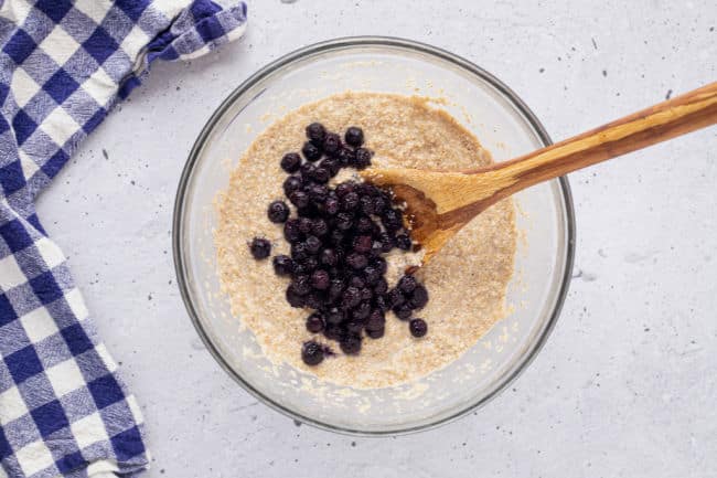 Stirring oat bran muffin batter with blueberries.