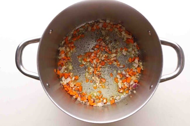 Sauteing onion and carrot in a pot.