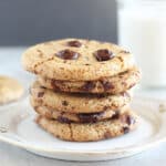 Chocolate chip cookies stacked on a white plate.