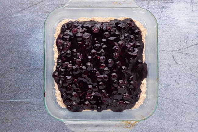Dough topped with blueberries in a baking dish.