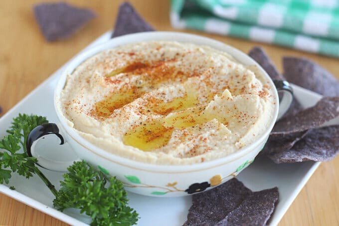 Creamy hummus in a bowl with tortilla chips.