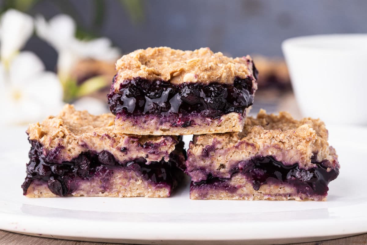 Stack of three blueberry pie bars on a plate.