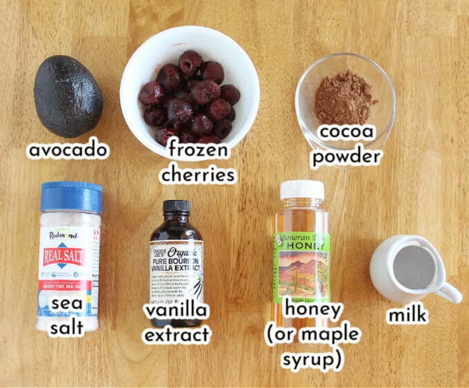 Various ingredients on a table, including cherries and cocoa powder.