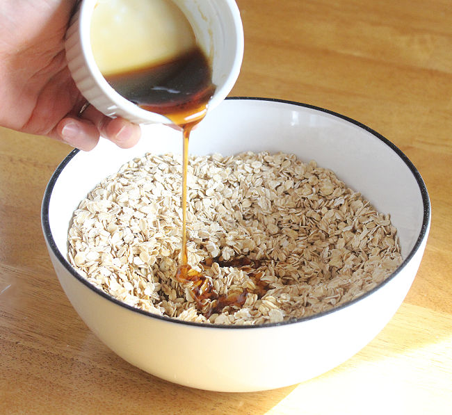 Pouring maple syrup into oats in a bowl.