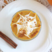 Overhead shot of an orange smoothie with a whipped cream spiderweb.