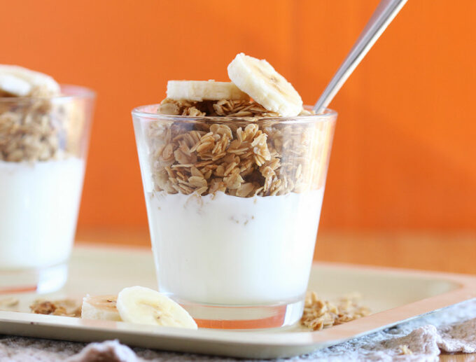 Small glass with yogurt on the bottom and granola on top.
