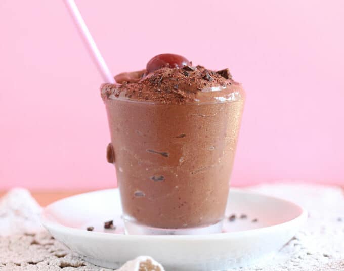 Chocolate ice cream overflowing a glass with a pink spoon.