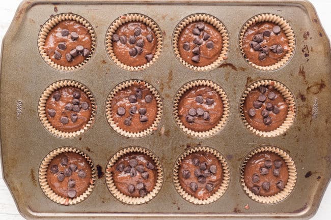 Unbaked chocolate cupcakes in a muffin tin.
