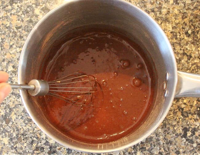 Chocolate mixture being whisked in a steel pot.