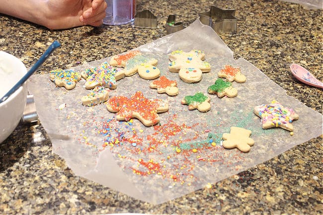 Decorating Christmas cookies with icing and sprinkles.
