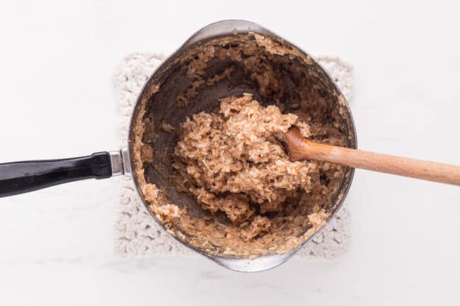 Stirring coconut and flour with butter in a pot.