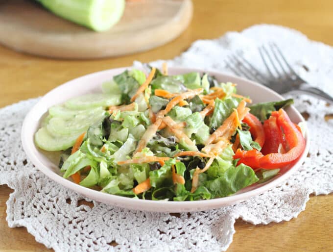 Salad and raw vegetables in a white bowl.