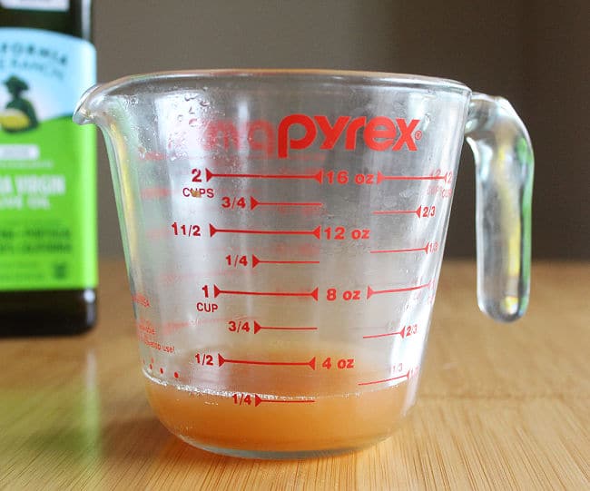 Two cup glass measuring pitcher filled with apple cider vinegar.