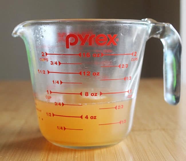 Glass measuring cup filled with gold liquid.