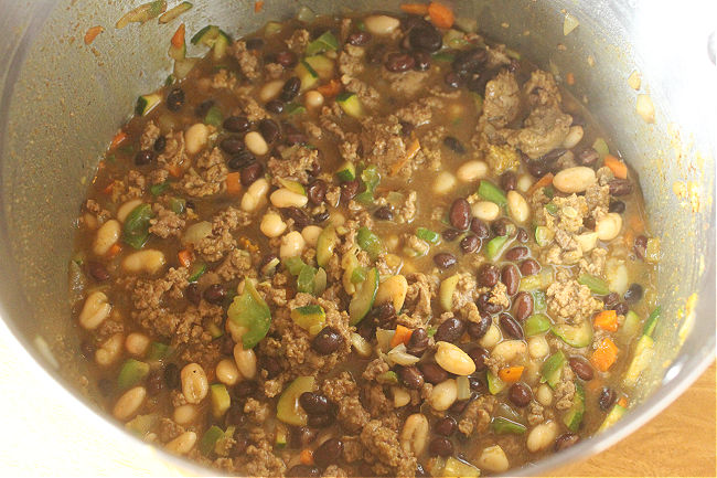 Simmering meat and beans in a large pot.