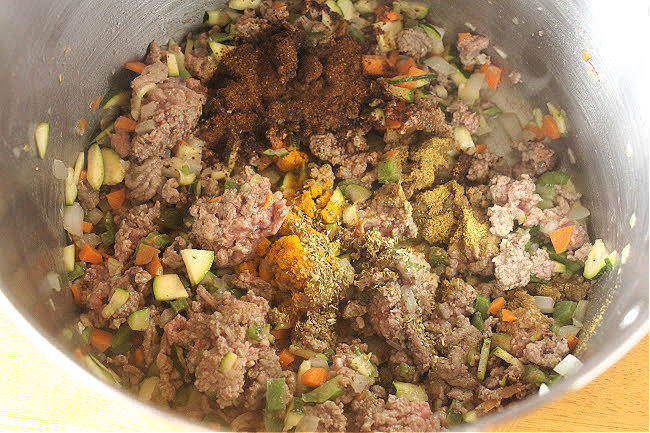 Meat and chili powder in a pot with various vegetables.