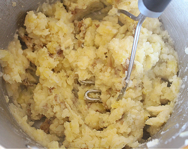 Potatoes being mashed in a pot.