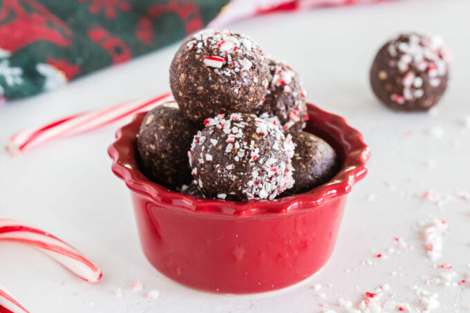Chocolate mint balls in a red bowls surrounded by candy canes.