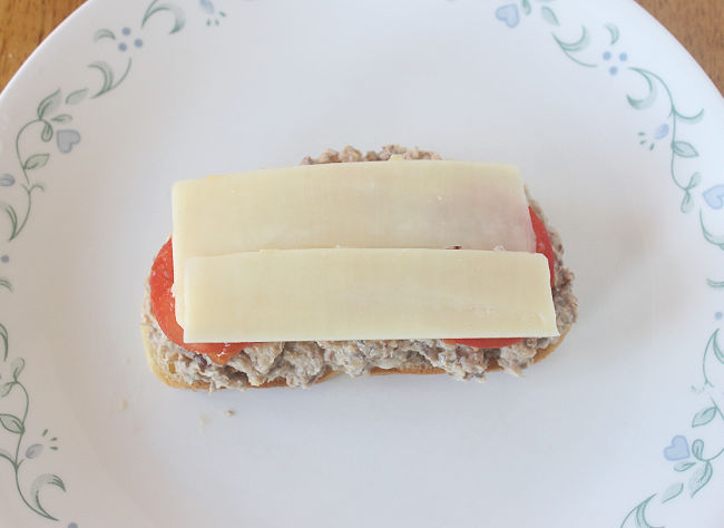 Toast topped with sardines, tomato, and cheese.