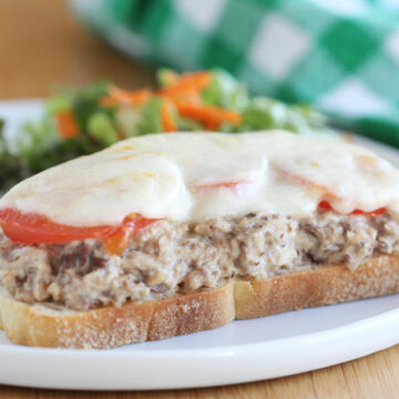 Sandwich topped with sardines, tomato, and cheese.