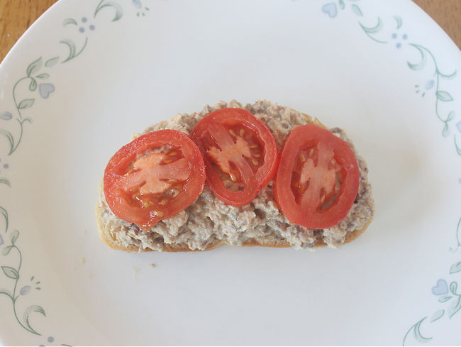 Toast topped with sardines and tomato slices.