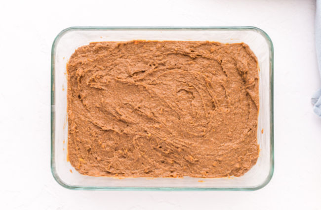 Unbaked brownie batter spread in a small dish.