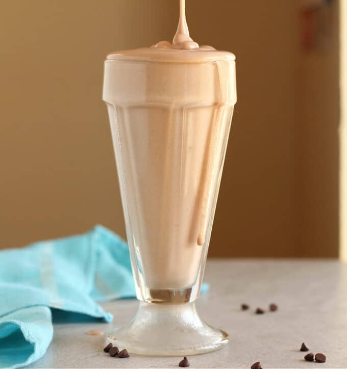 Chocolate shake being poured into a tall glass.