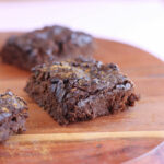 Brownie square on a wood cutting board.