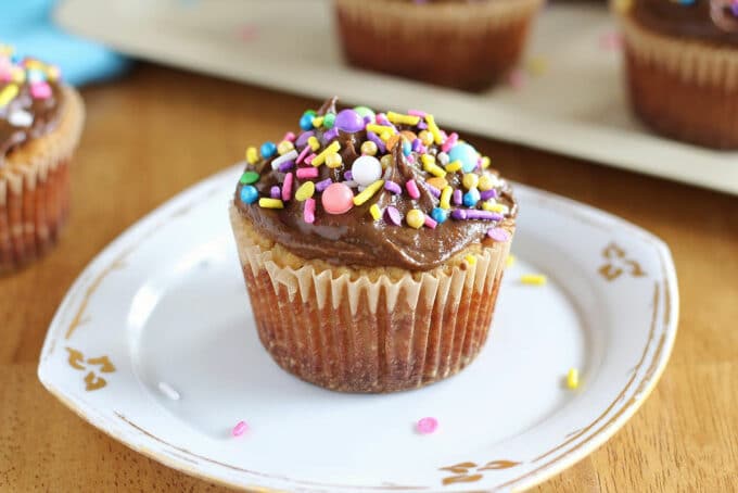 Vanilla cupcake with frosting on a white plate.