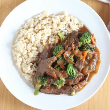 Beef, broccoli, vegetables, and rice on a white plate.