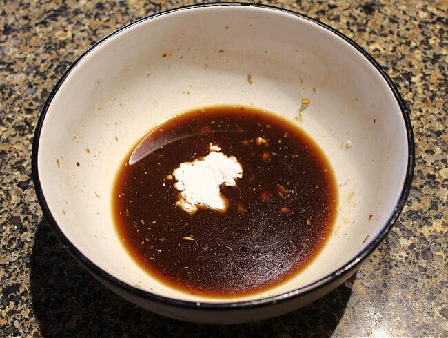 Arrowroot in a soy sauce-based marinade all in a large white bowl.