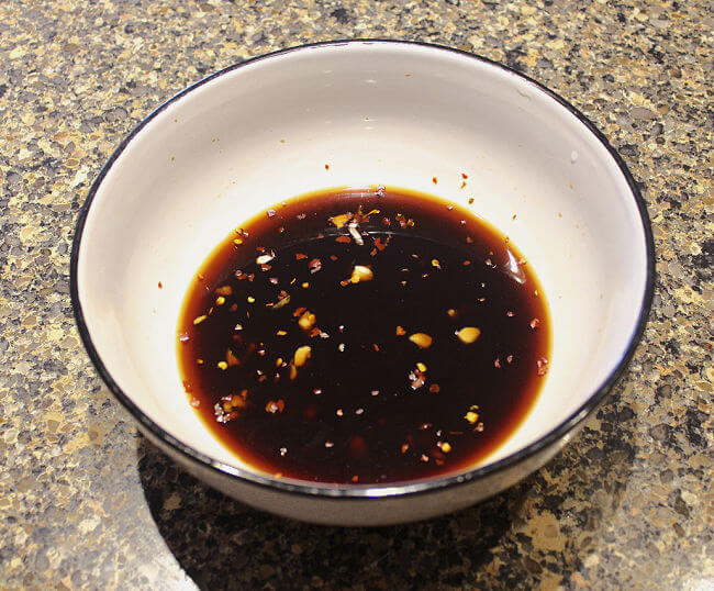 Soy sauce, garlic, ginger, honey, red pepper flakes mixed together in a large white bowl.