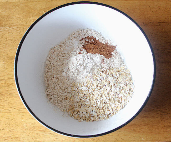 Flour, oats, salt, and baking soda in a large white bowl.