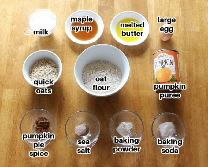 Ingredients for a muffin recipe laid out on a wood table.