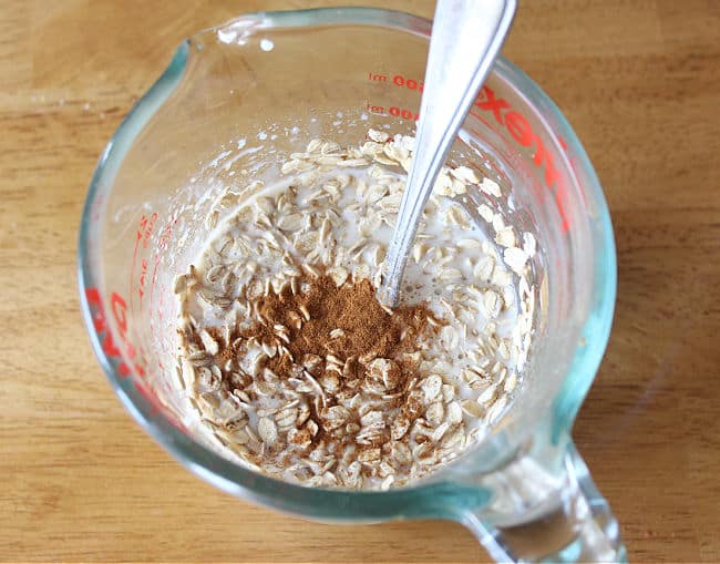 Milk, oats, and cinnamon being stirred together.