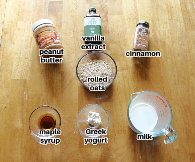 Various ingredients laid out on a wood table, including oats and peanut butter.