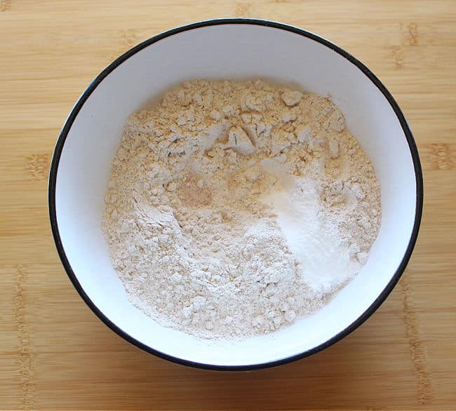 Flour, baking powder, and salt in a large white bowl.