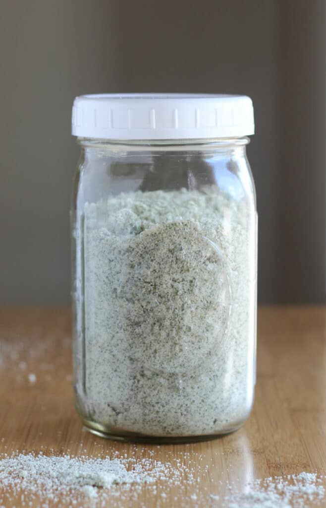 Glass jar with white lid filled with green flour.