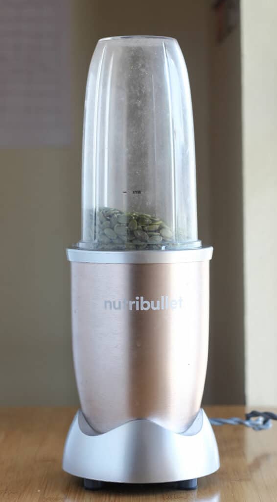 Nutribullet 900 blender fitted with a blender cup filled with pumpkin seeds.