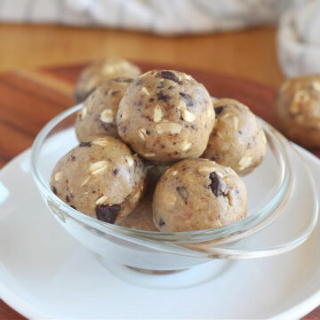 Dough balls in a clear glass bowl on a white plate.