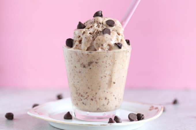 Glass cup full of ice cream with chocolate chips.