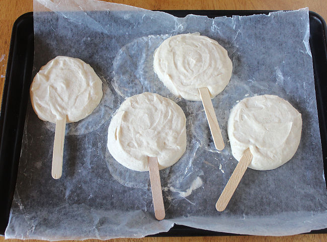 Frozen Greek yogurt pops on a wax paper-lined baking sheet.