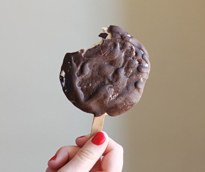 Hand holding a chocolate covered ice cream pop.