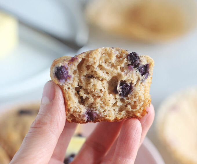 Hand holding half of a blueberry muffin.