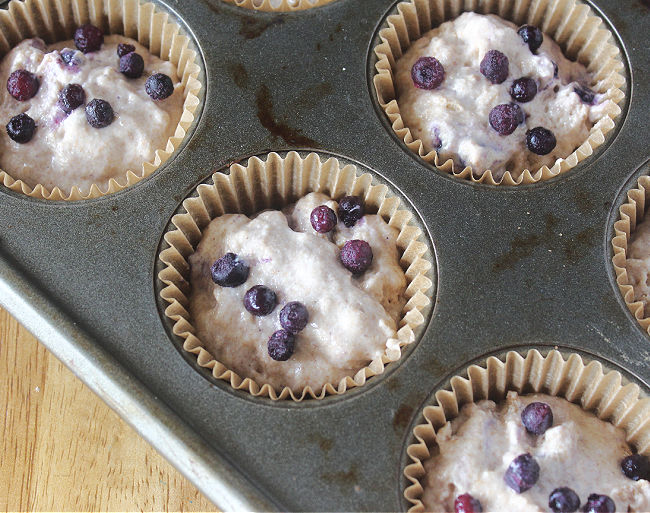 Unbaked blueberry muffins in paper muffin cups.