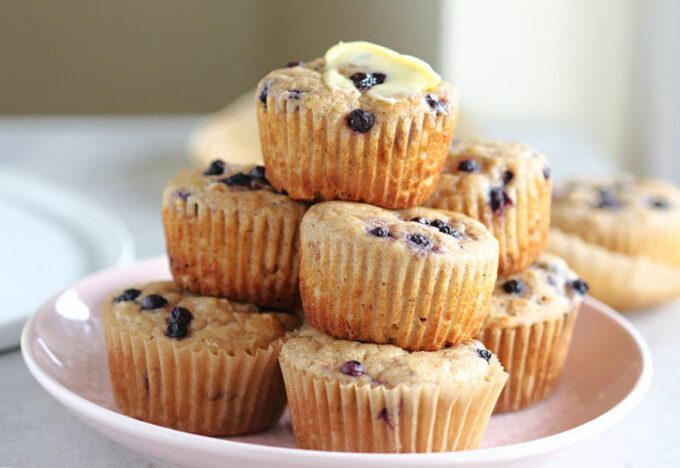 Stack of blueberry muffins on a pink plate.
